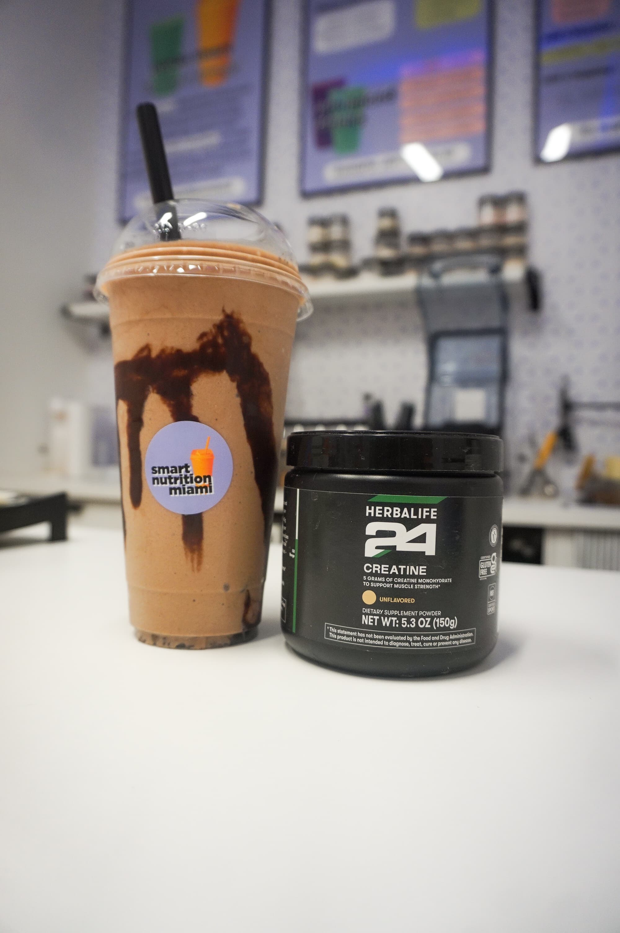 Chocolate smoothie with chocolate drizzle beside a container of Herbalife 24 creatine dietary supplement.