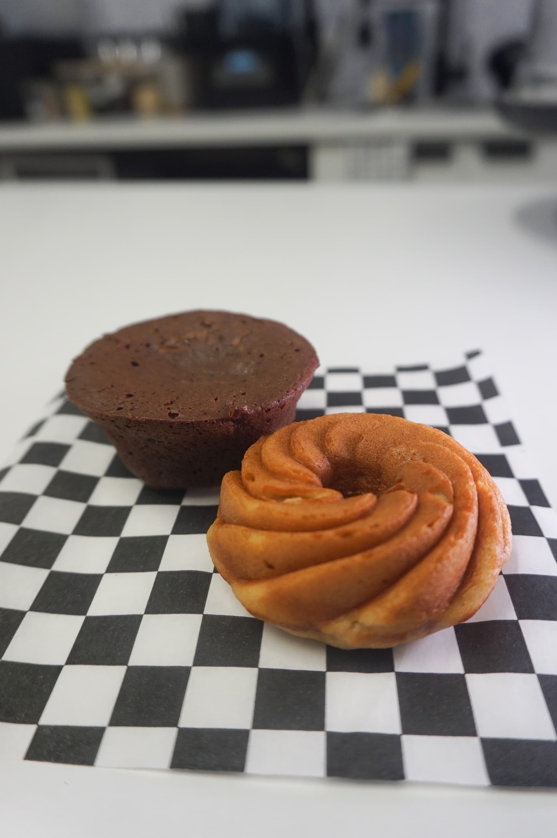 Chocolate brownie and a golden swirled pastry on a black and white checkered paper.