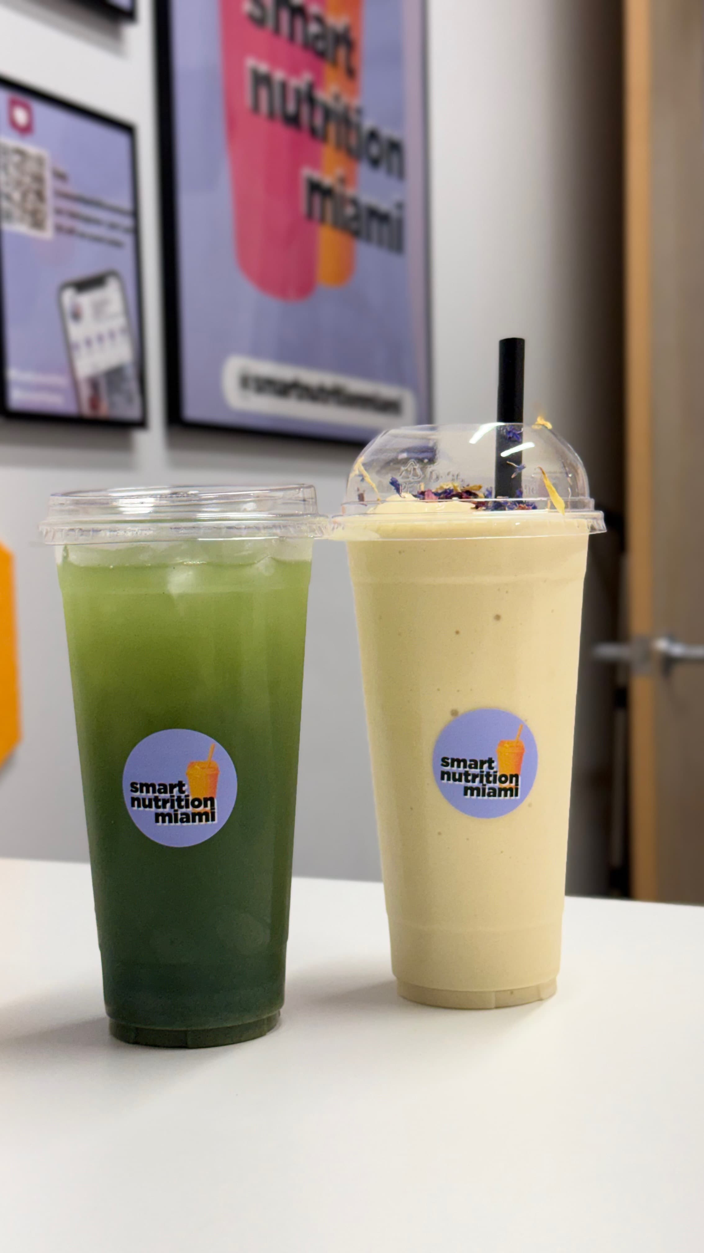 Green iced drink and a yellow smoothie with flower toppings from Smart Nutrition Miami.